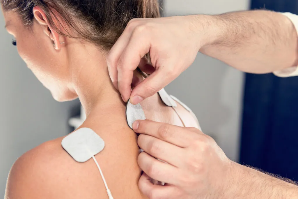 Physical therapist applying TENS treatment to patient